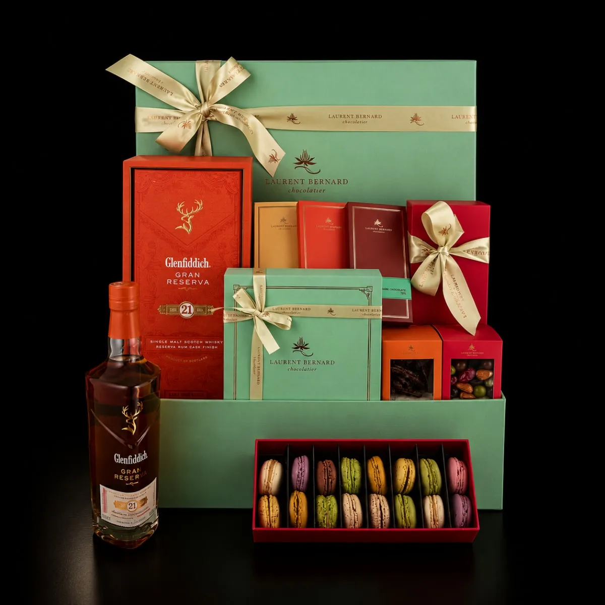 Luxury whisky and chocolate gift hamper by Laurent Bernard featuring Glenfiddich 21 Year Old, premium chocolates, gift boxes and colorful macarons in an elegant black setting.