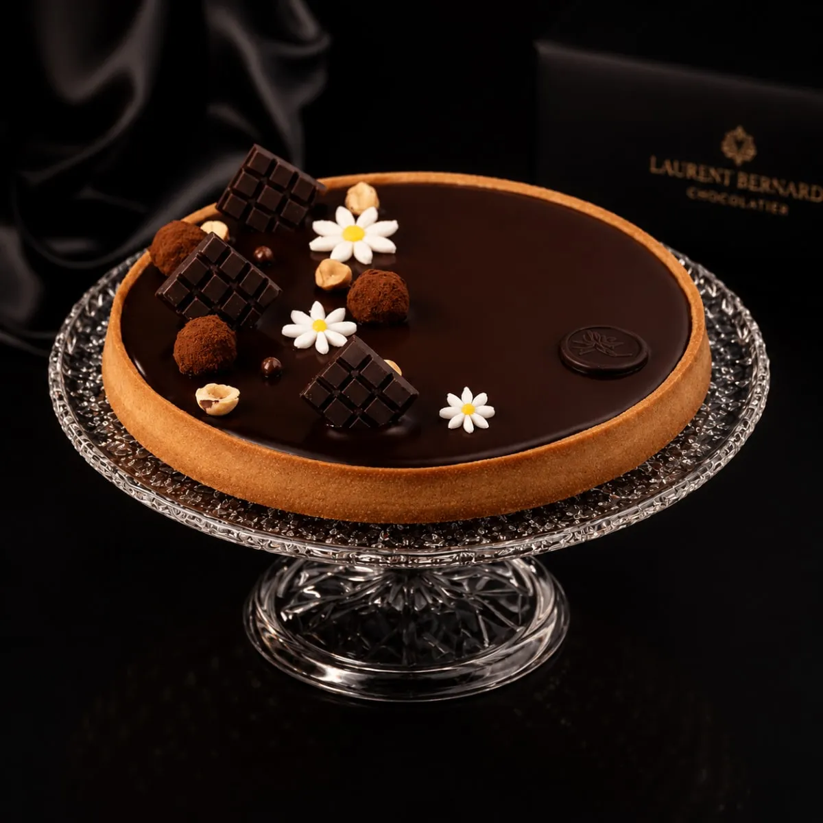 Dark chocolate tart on crystal cake stand, black background